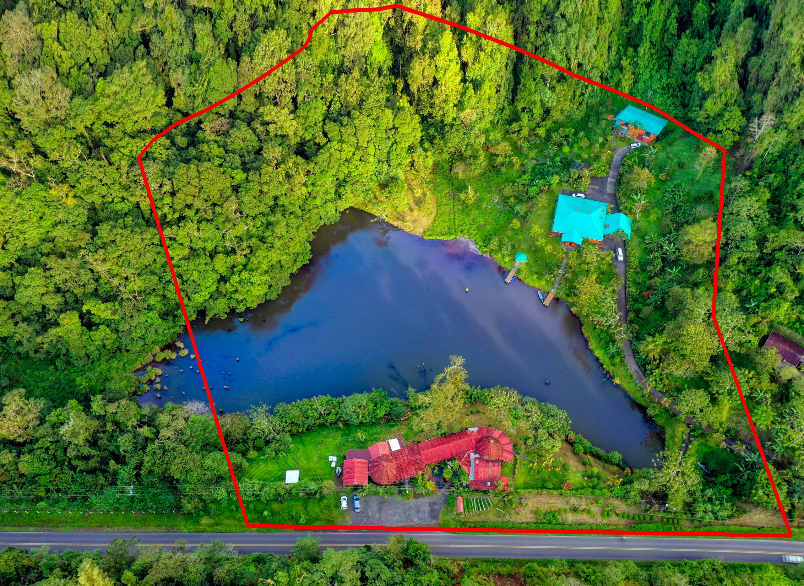 Aerial drone view of a Costa Rica investment property showing the Lucky Bug estate, private lake, and surrounding rainforest.