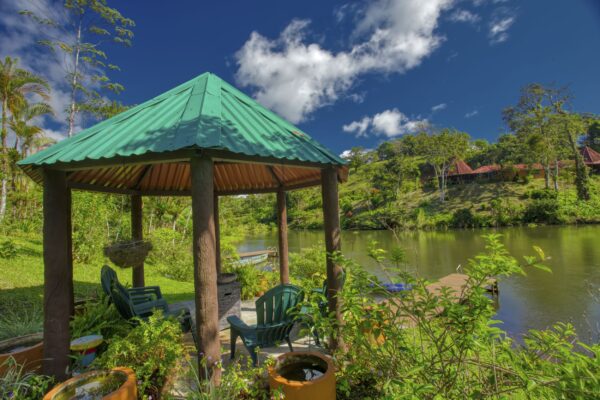 View of the private lake at the Lucky Bug Property in Costa Rica from the gazebo, with dock and kayak visible among the tropical surroundings